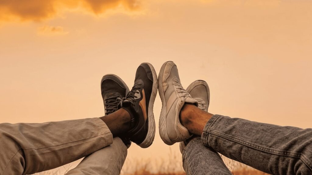 Two friends relaxing outdoors in sneakers during sunset, symbolizing peace, digital detox, and life beyond social media