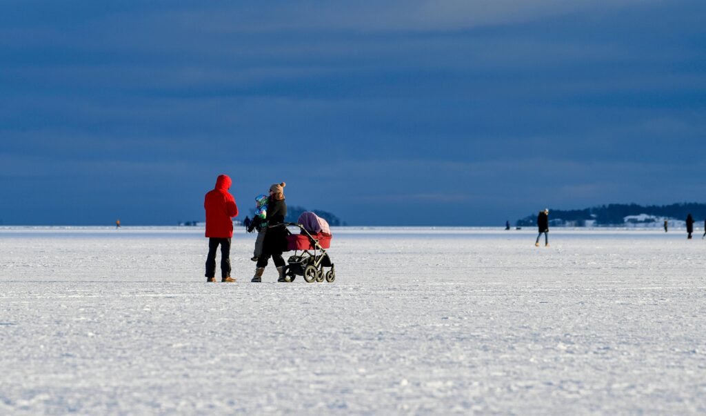 Family walking on a frozen lake in winter with snow landscape and cloudy sky in finland
